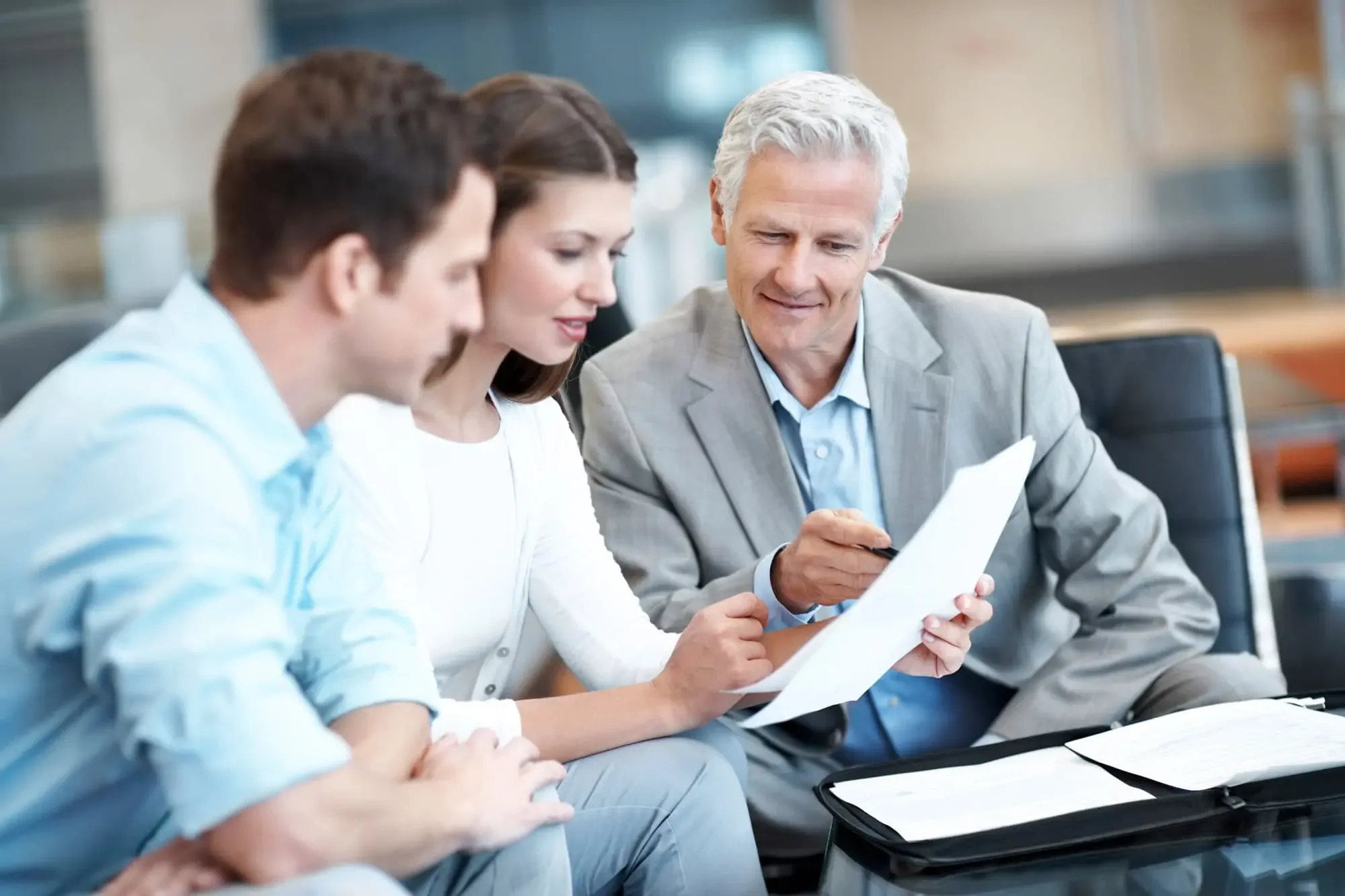 Financial advisor reviewing a document with a young couple in an office