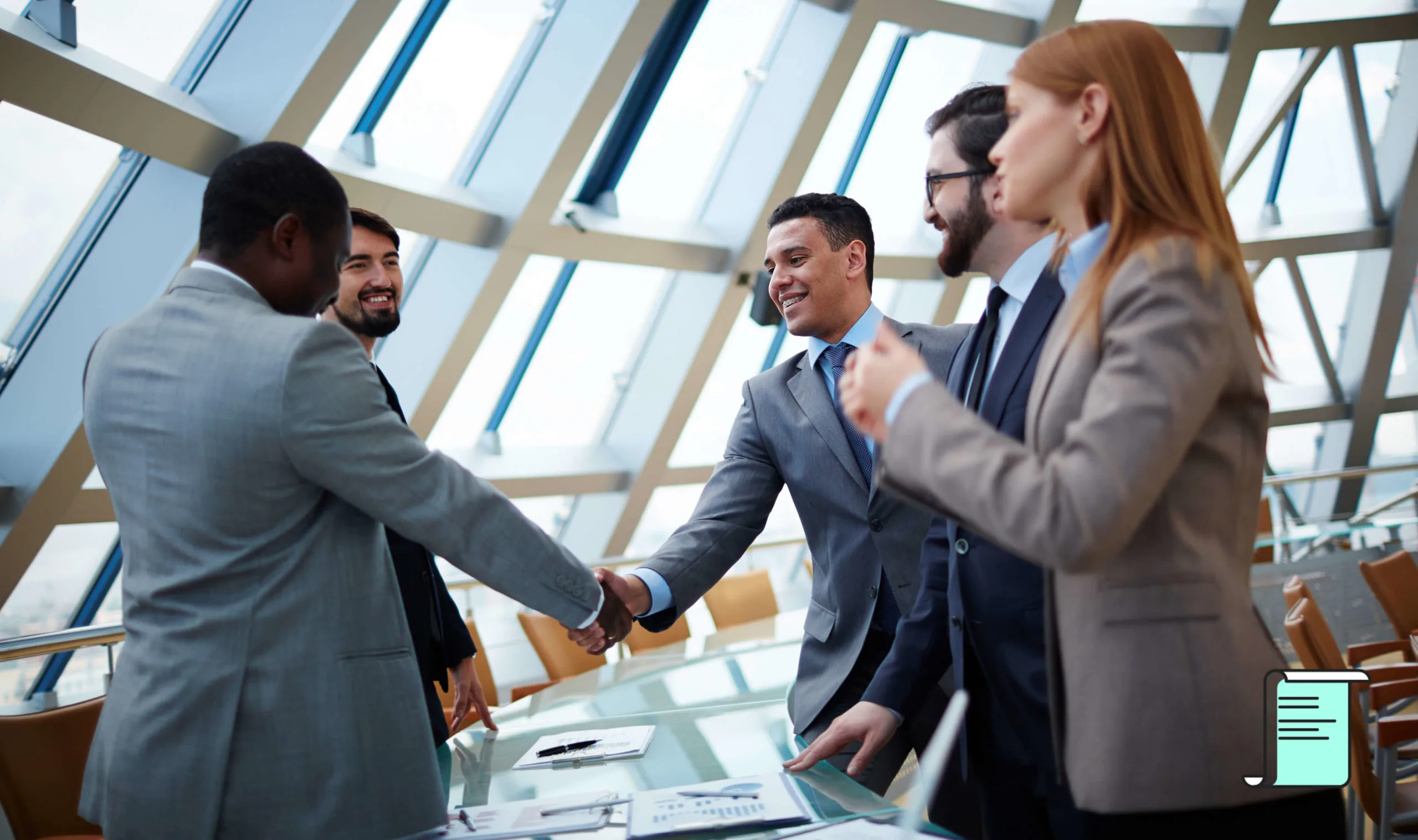 Business professionals shaking hands across a conference table in a glass-walled office